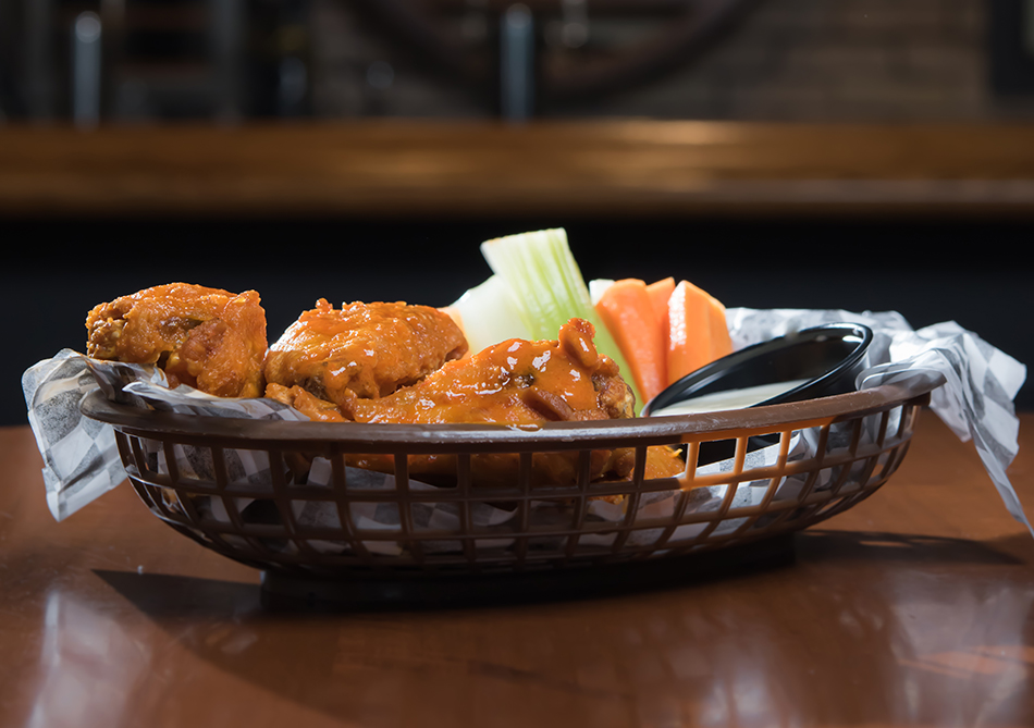 breaded chicken wings served in a basket with celery sticks and carrots